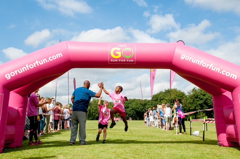 A young runner jumps to high five Mark Lewis Francis as he crosses the finish line in Norwich Sports Minister Helen Grant Supports Go Run For Fun and Welcomes Efforts to Make Sport Fun for Children